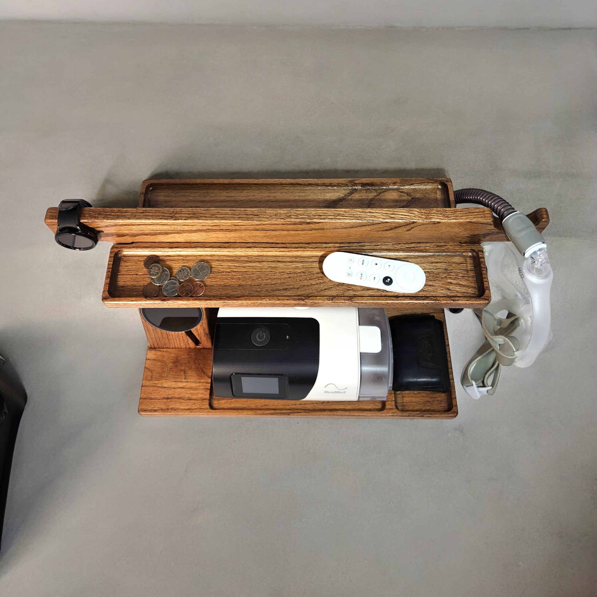 A top view of the CPAP Smart Stand made by Custom Cave Works.  The stand is made from solid Oak wood and shows a very organized view of the catch-all trans, including the one on the back side of the stand.  