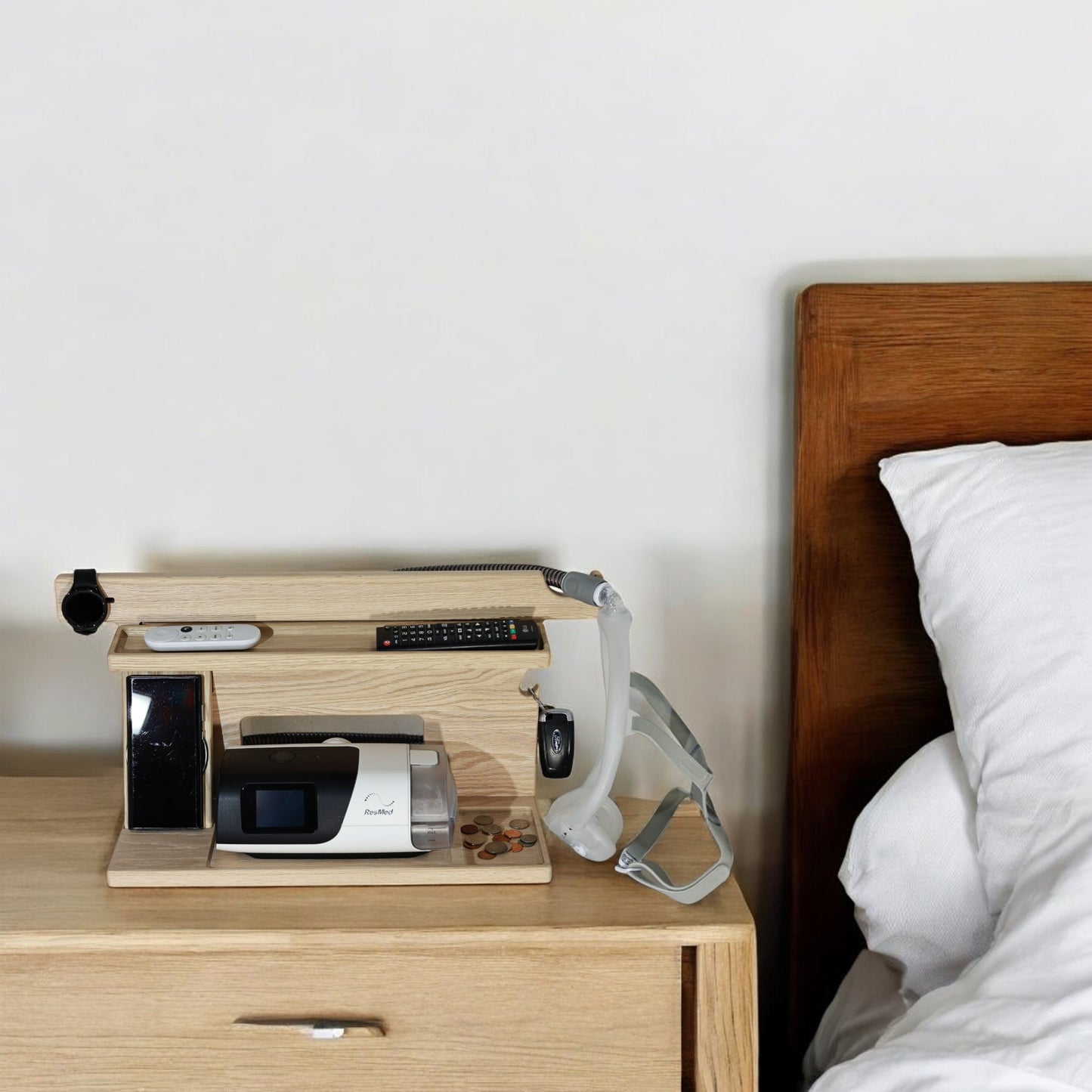 A large CPAP dock next to a bed on a nightstand.  This helps organize your nightstand and keeps the keys, change, wallet, remotes and electronic devices from cluttering the nightstand.